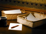 Sweetgrass Writer's Tray and Sweetgrass Letter Tray on a desk with letterhead, envelopes, pen, and coffee cup. Basket hand crafted of brown ash and sweet grass by Stephen Zeh of Temple, Maine.